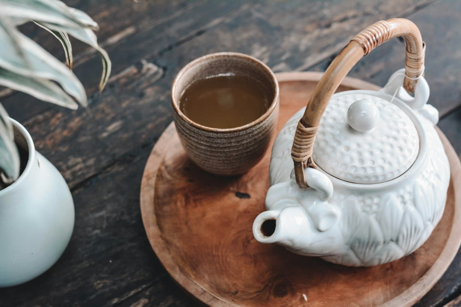 Porcelain teapot and clay cup arranged on a turned wooden tray